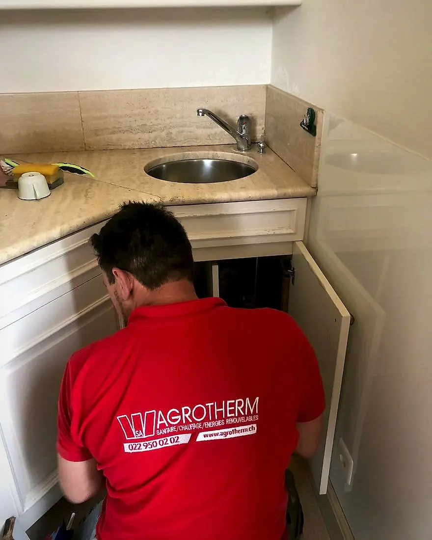 Emergency plumbing: an Agrotherm technician at work under a sink