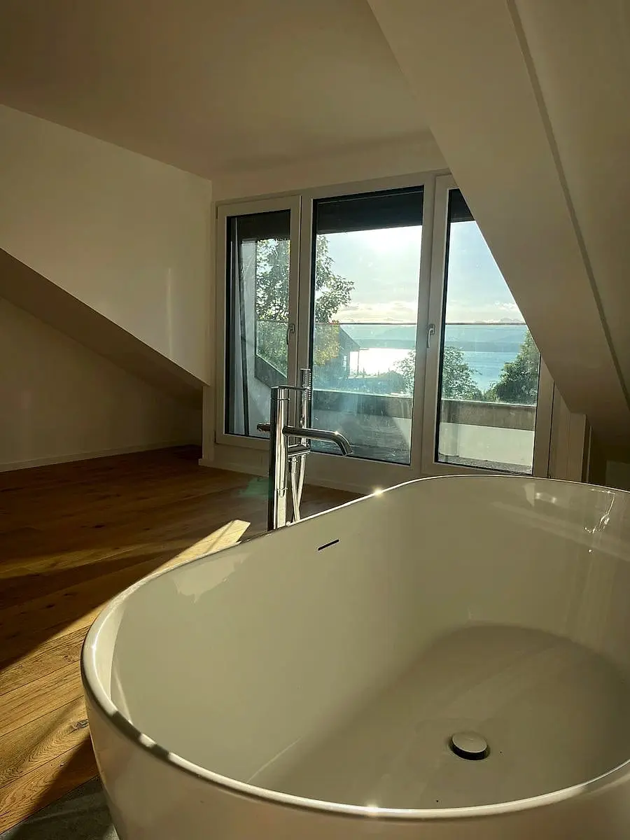 Mansion in Cologny: freestanding bathtub under the eaves with a view of Lake Geneva, by Agrotherm