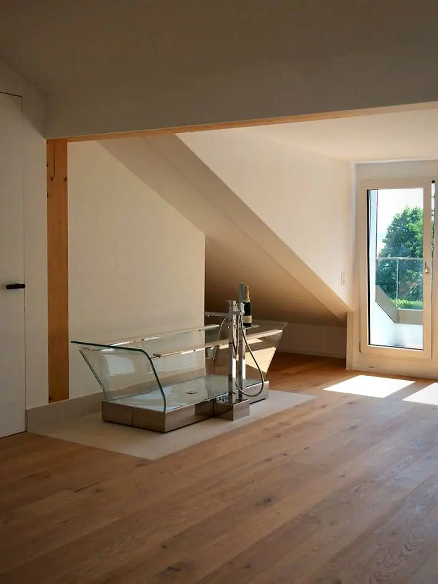 Attic bathroom with a glass bathtub on a stainless steel base, installed by Agrotherm in Bellevue
